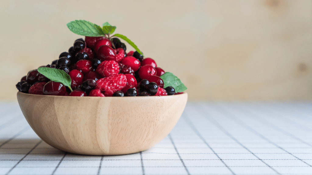 a wooden bowl filled with raspberries and blackberries