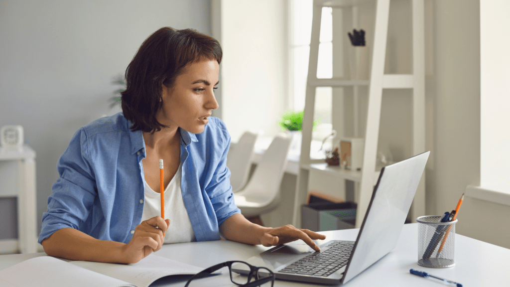 A woman smiling and using a laptop in an office