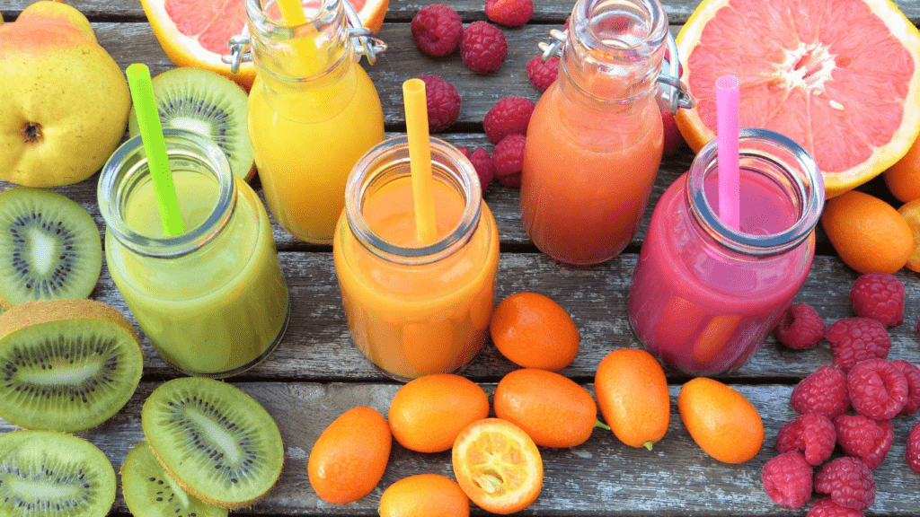 various fruits and juices are sitting on a wooden table