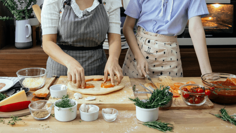 two people in aprons preparing food in the kitchen