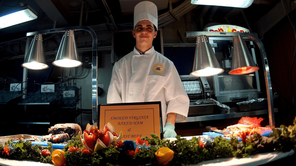 a chef standing in front of a table with food on it