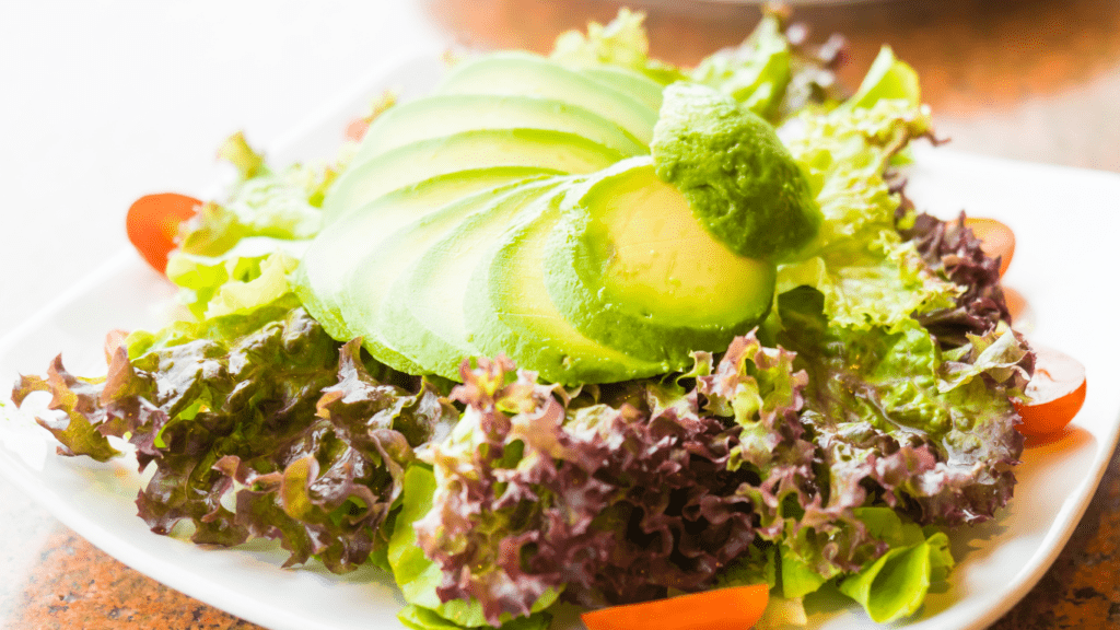 a salad with avocado and tomatoes on a white plate