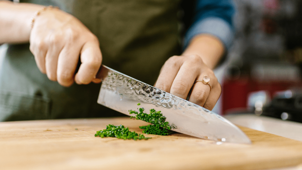 a person cutting with a knife on a cutting board