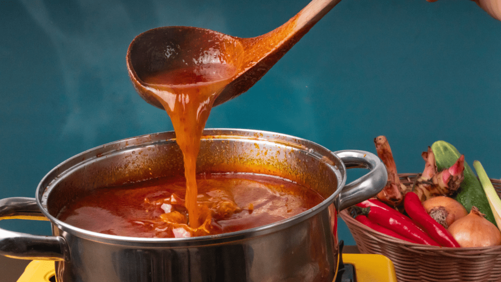 a person pouring sauce into a pot on a stove