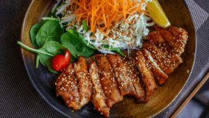 a plate with chicken, salad and sesame seeds