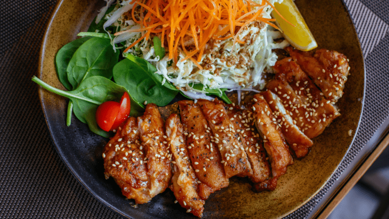 a plate with chicken, salad and sesame seeds