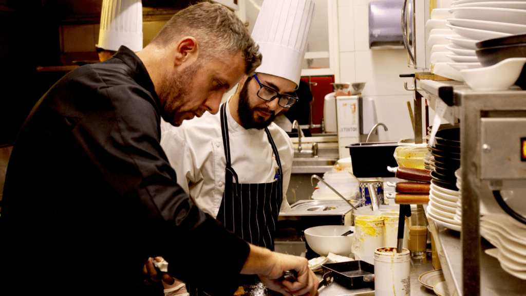 a chef standing in front of a table with food on it