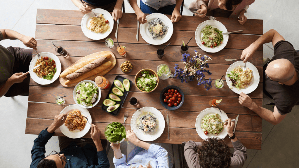 a group of people sitting around a dinner table with food