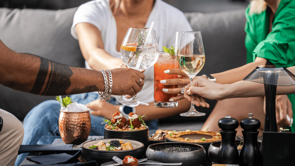 a group of people sitting at a table with food and drinks