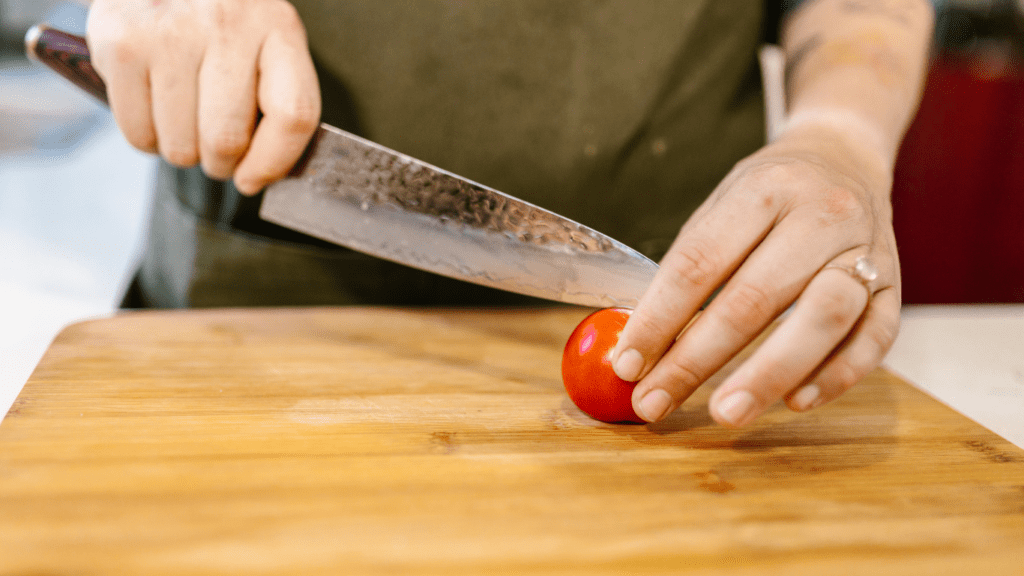 a person cutting with a knife on a cutting board