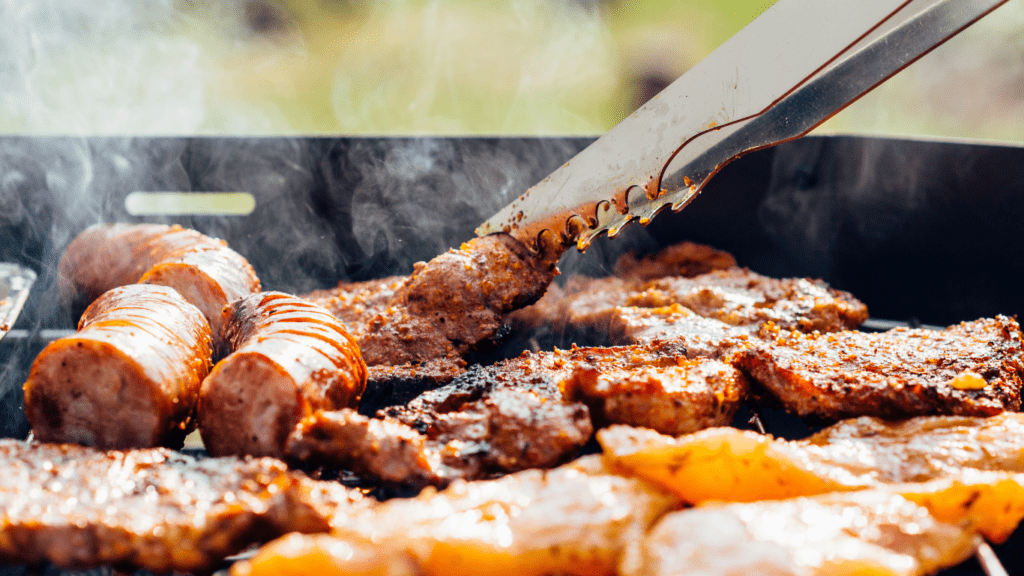 a person grilling meat on a grill with smoke coming out of it