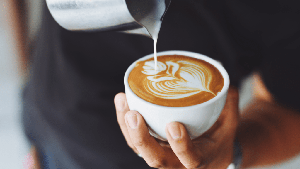 a person holding a cup of coffee with a latte art