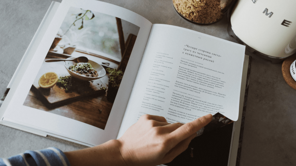 a person holding an open cookbook with food on it