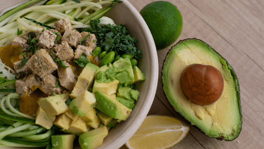 a salad with avocado and tomatoes on a white plate