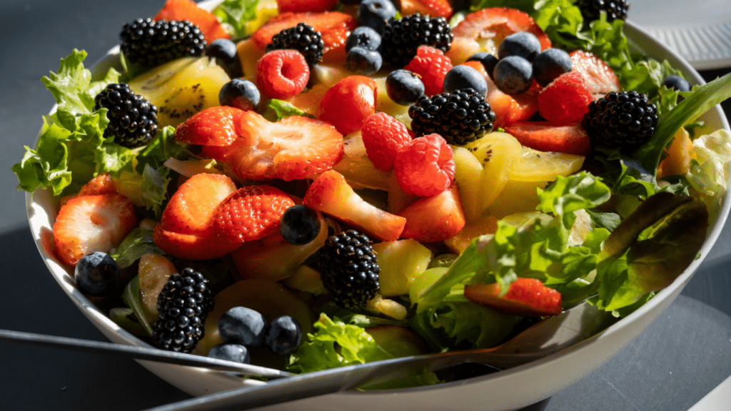 a wooden bowl filled with raspberries and blackberries