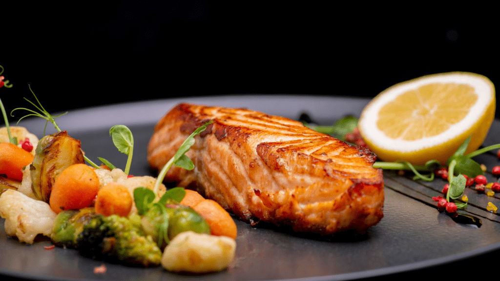 grilled salmon on a black plate with vegetables